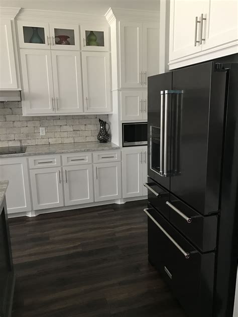 black stainless steel appliances with white cabinets|black fridge in white kitchen.